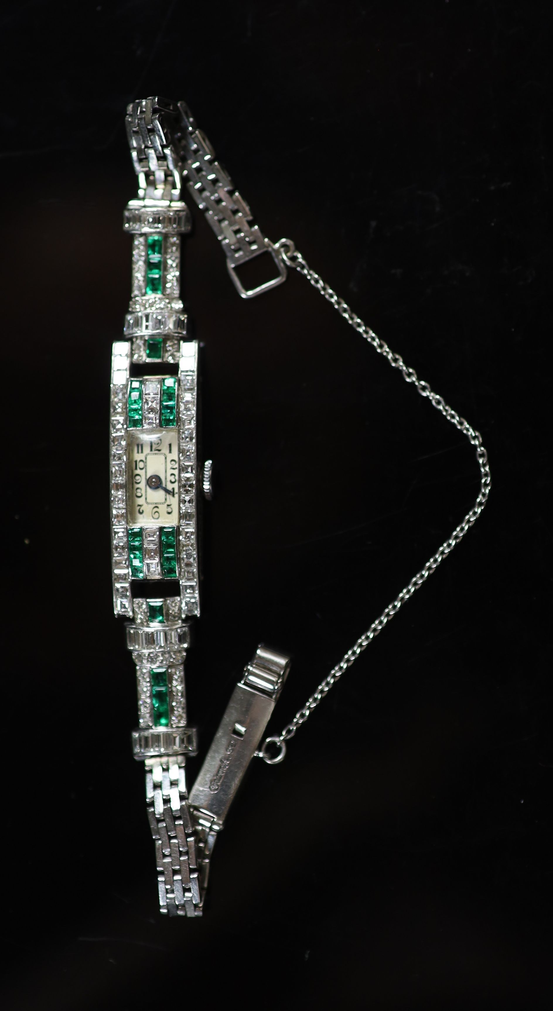 A lady's 1940's/1950's engraved platinum, emerald and diamond set manual wind rectangular cocktail watch, on a 9ct white gold bracelet